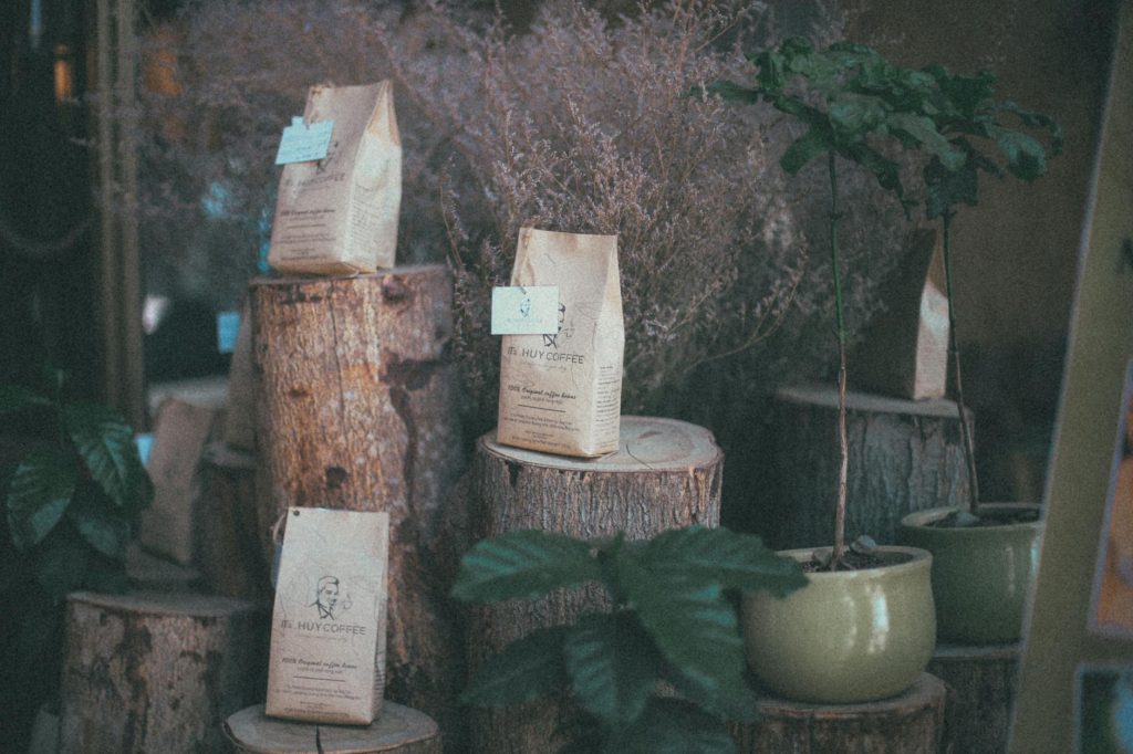 Charming rustic coffee bags displayed on wood logs with vintage touch and greenery.