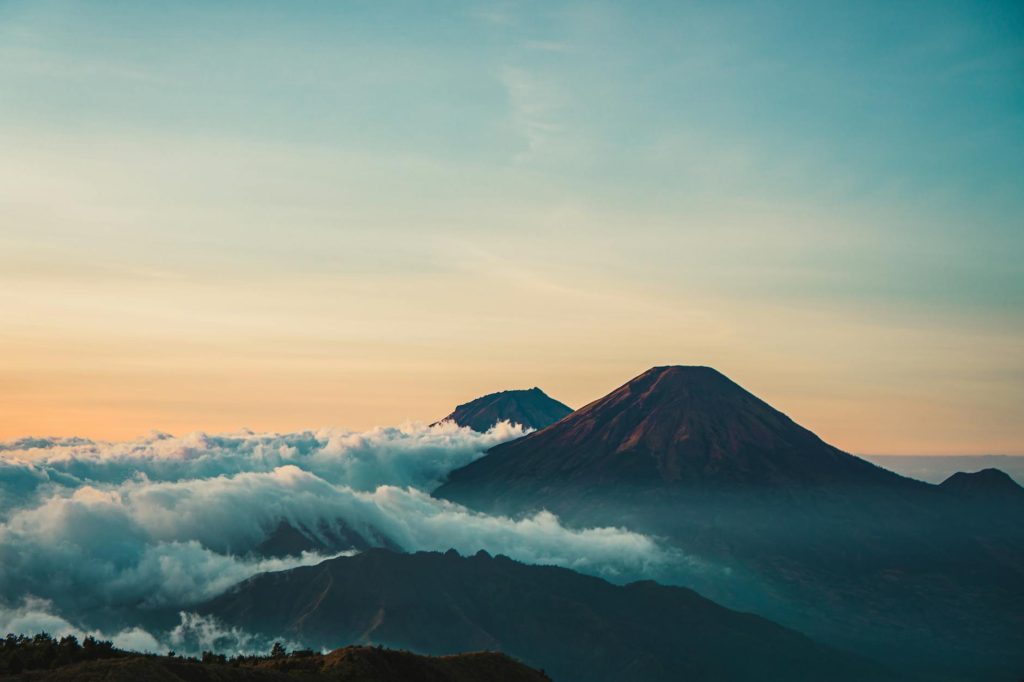 Beautiful sunrise view of Mount Sindoro with clouds and serene landscape in Java, Indonesia.