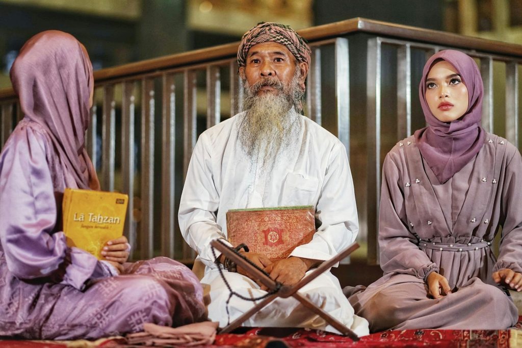 A group of people in traditional attire reading religious texts indoors in Jakarta, Indonesia.