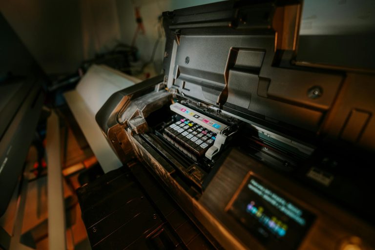 Close-up view of an inkjet printer with exposed cartridges in a workspace setting.