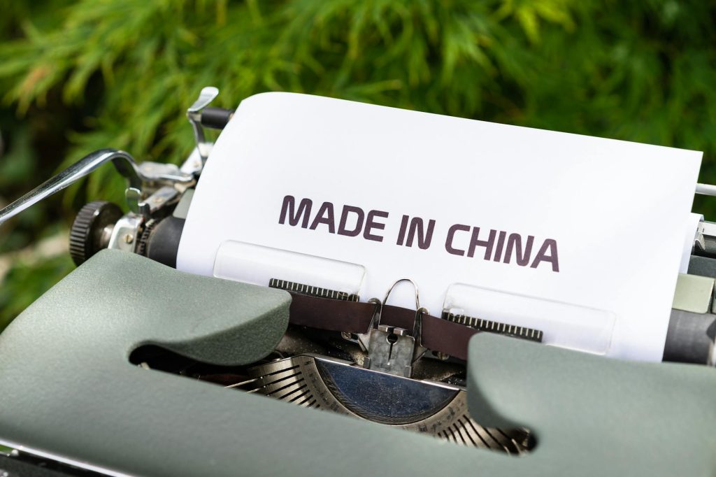 Close-up of a vintage typewriter with 'Made in China' typed, set in an outdoor environment.