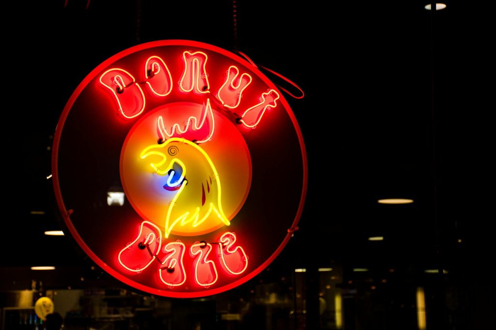 Illuminated neon sign of a Donut Cafe with colorful lights in the dark.