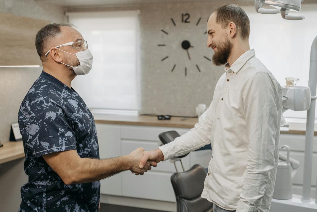 Dentist and patient handshake in a modern clinic setting. Professional healthcare interaction.