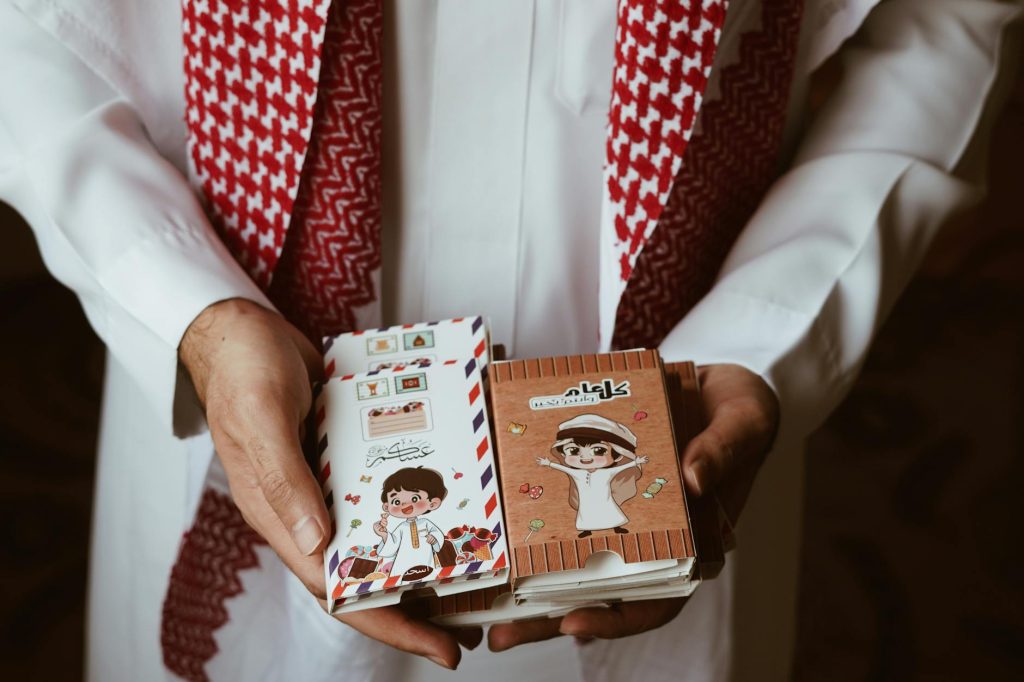 A man holds colorful, traditional Arabic cards in his hands, showcasing intricate designs.