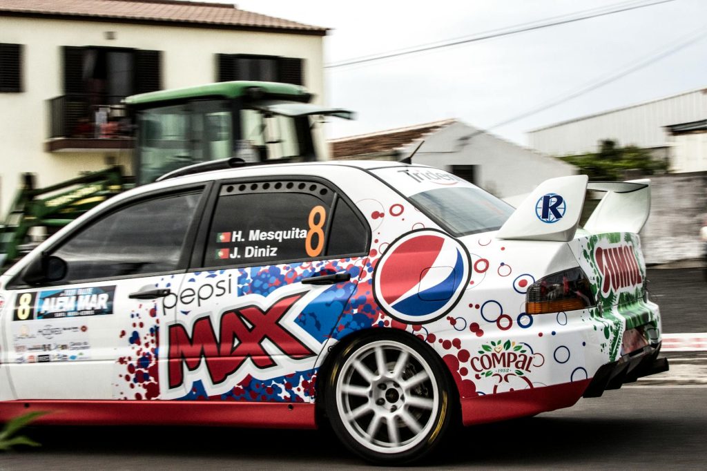 Dynamic shot of a colorful race car speeding through Açores, Portugal, capturing the thrill of motorsports.