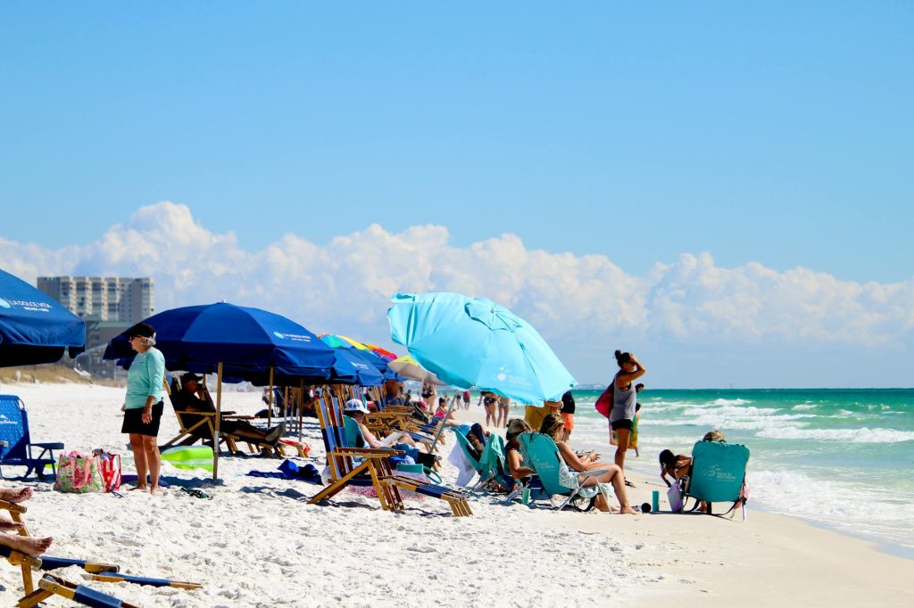 Vibrant beach scene with umbrellas and people enjoying a sunny summer day by the sea.