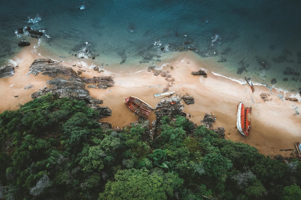 Aerial shot of Kemaman coast, showcasing shipwrecks on a sandy beach with lush greenery.