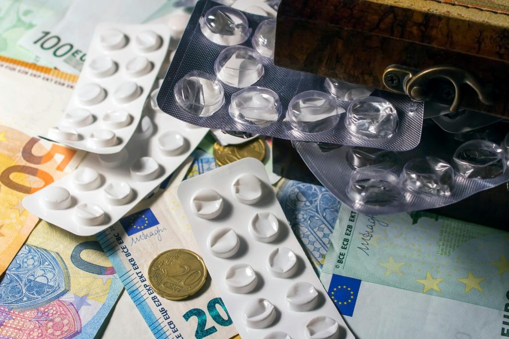 Blister packs of medication placed on Euro banknotes, illustrating healthcare expenses.