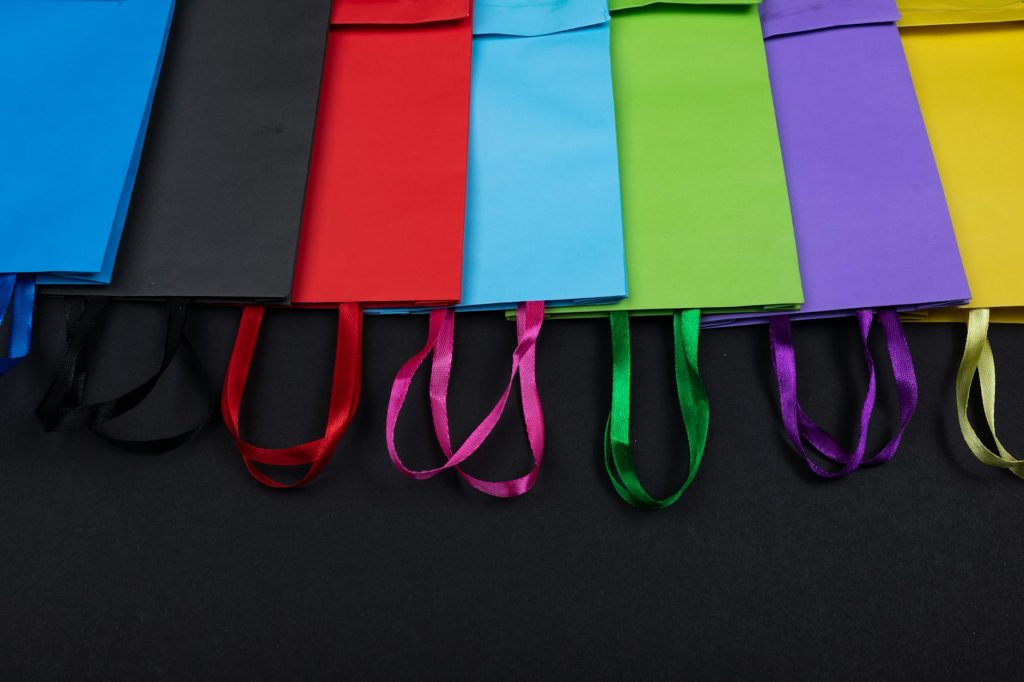 Brightly colored paper shopping bags arranged on a black background, highlighting vivid colors.