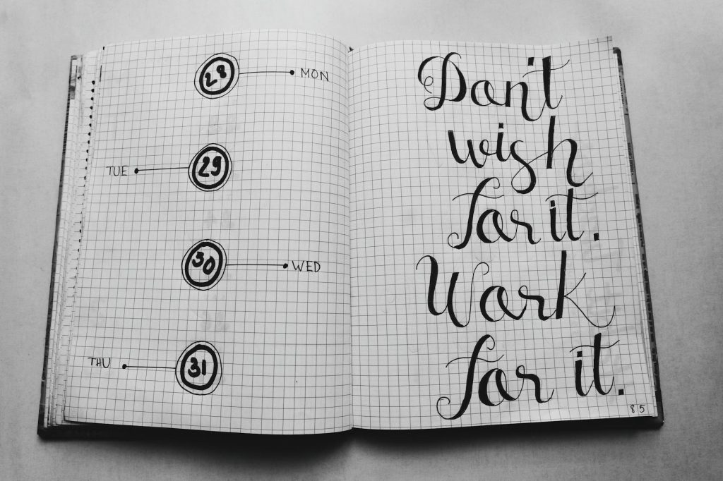 Open planner notebook with motivational quote in artistic handwriting. Organized layout, perfect for goal setting.