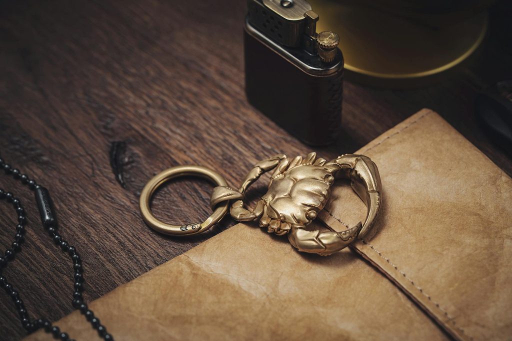 Close-up of a golden crab keychain set on a wooden desk with vintage items, showcasing luxury and style.