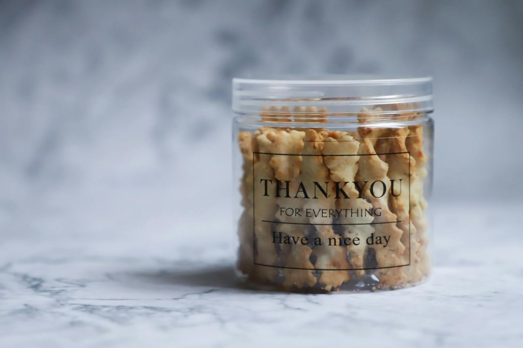 A clear container filled with cookies, featuring a thank you message. Perfect gift idea.
