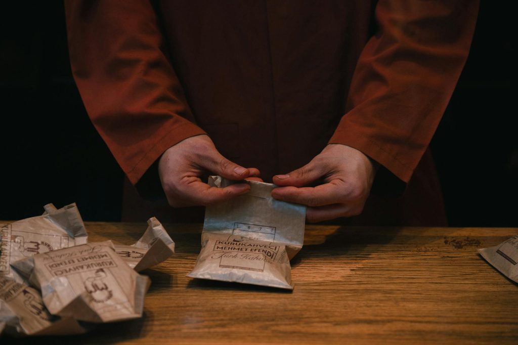 A barista carefully folds coffee bags at an artisan coffee shop, creating an authentic and warm atmosphere.