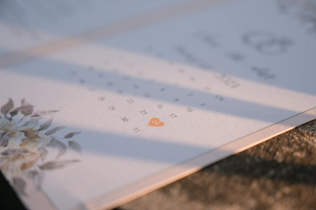 Close-up of an elegant floral-themed wedding invitation on a sunny day.