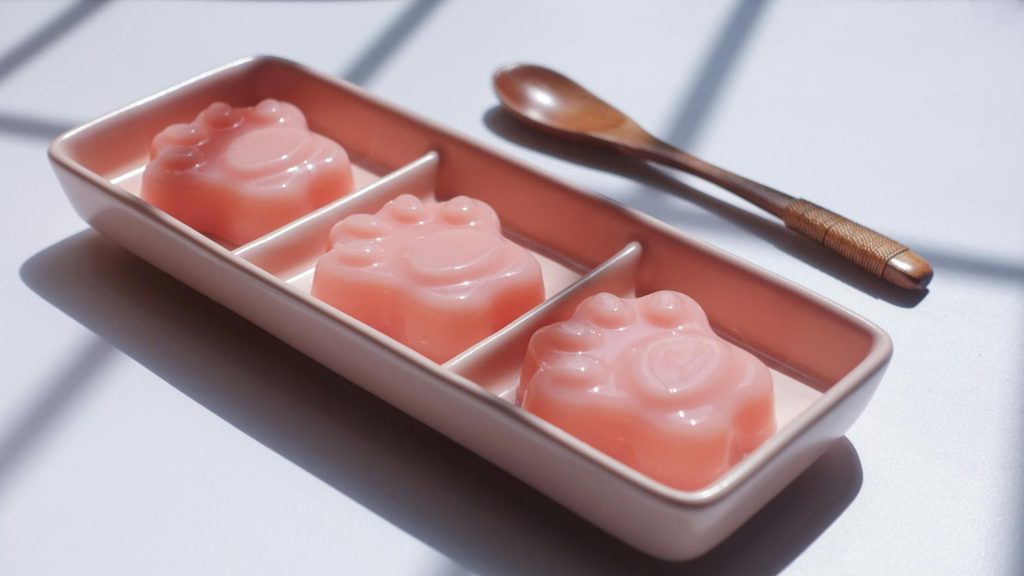 Artistic photo of pink paw-shaped soap, elegantly presented on a tray with a wooden spoon.