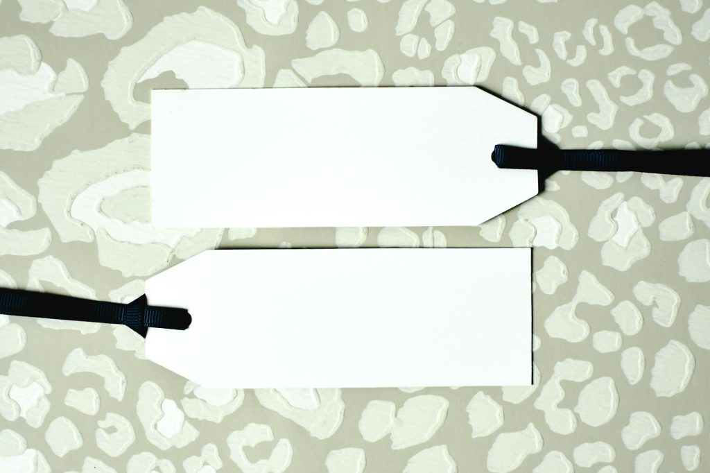 Two blank price tags with black ribbons on a patterned background, perfect for design mockups.