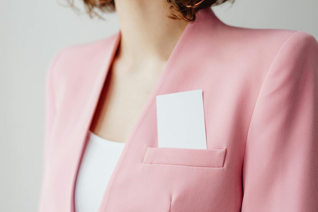 Elegant pink blazer with business card in pocket for a professional look.