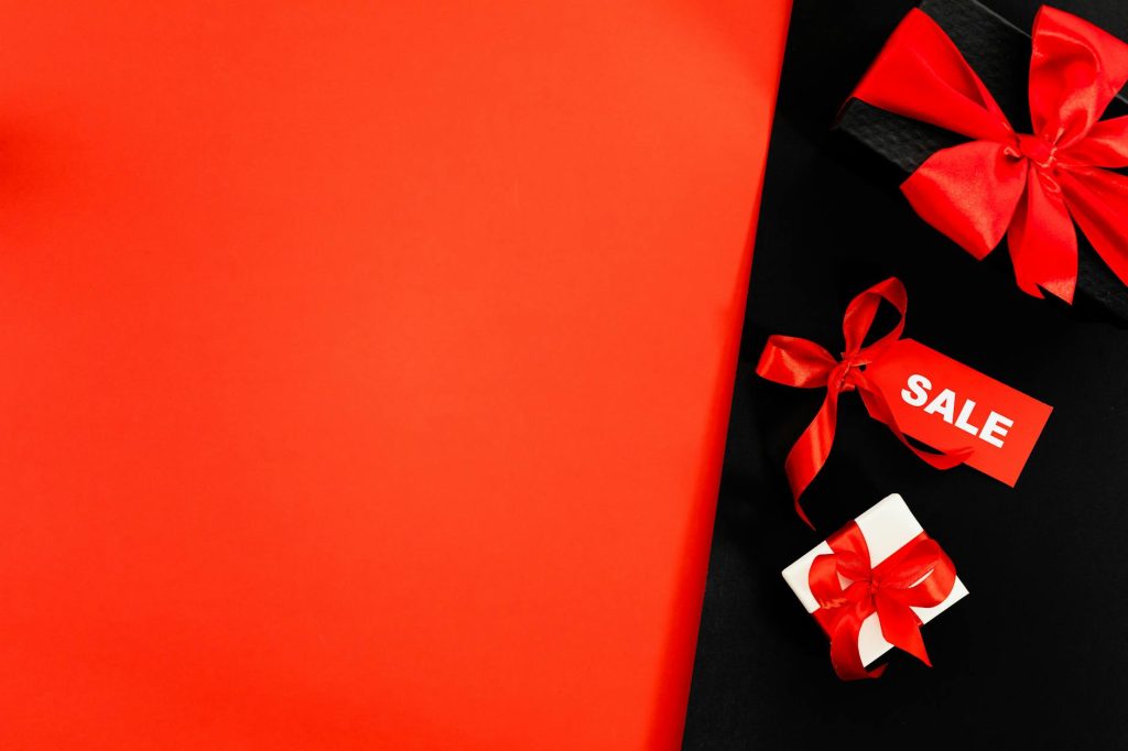 Red gift boxes with ribbons and sale tag on red background, perfect for marketing.