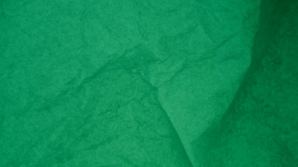 Detailed view of an emerald green wrinkled paper texture for backgrounds or designs.