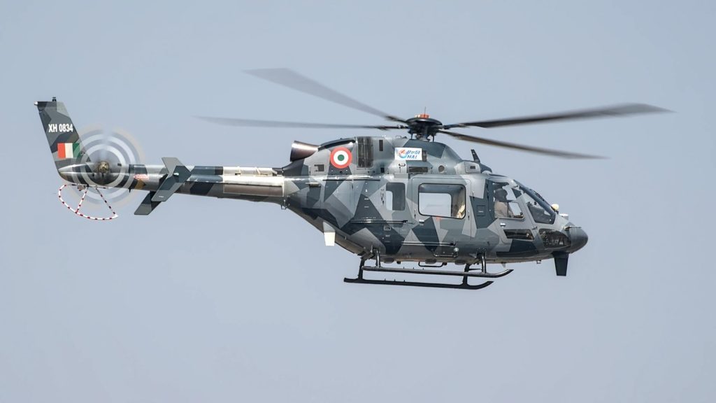 A military helicopter flies at an airshow in Bengaluru, showcasing advanced technology.