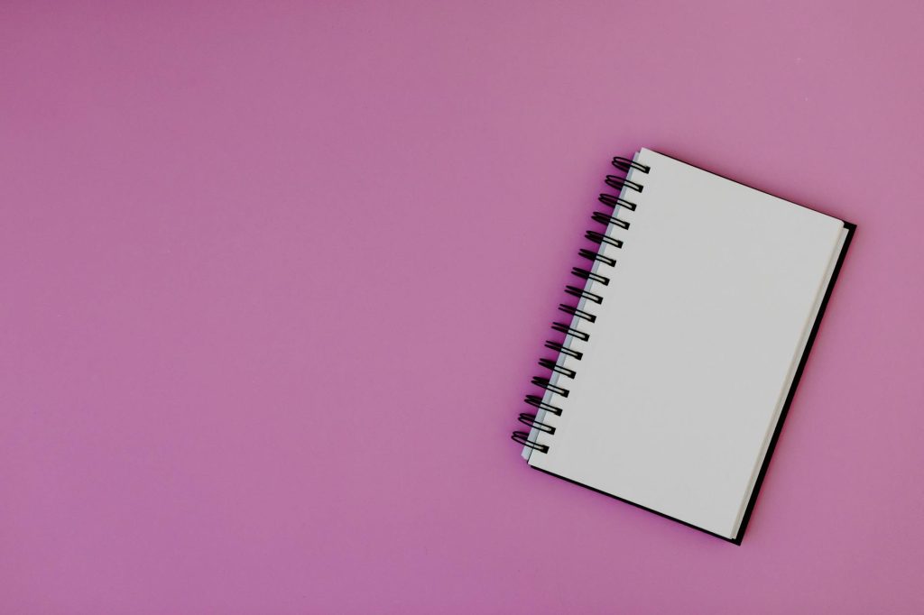 Top view of a spiral notebook on a pink background, suitable for mockups.