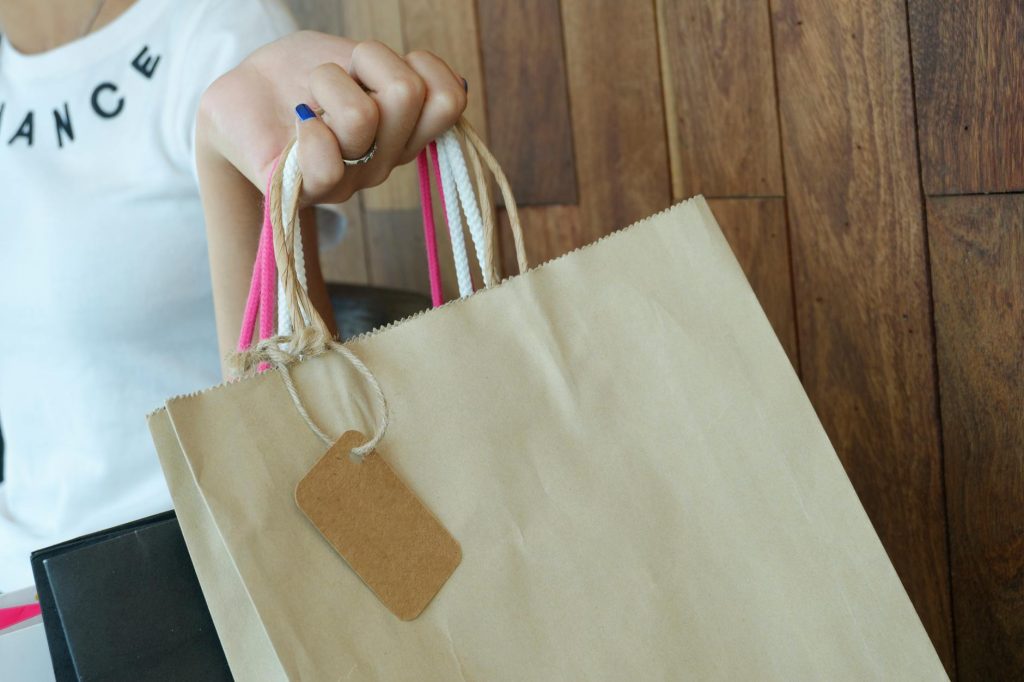 Close-up of a woman holding shopping bags with wooden background.
