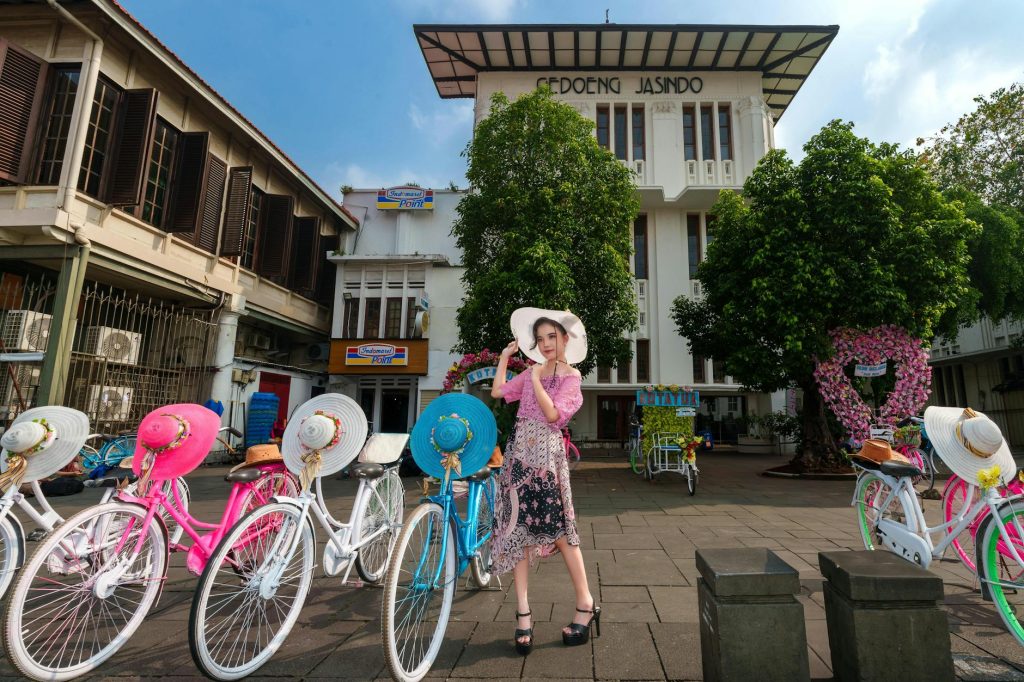 A woman poses in front of vibrant bicycles near Gedoeng Jasindo, Jakarta.