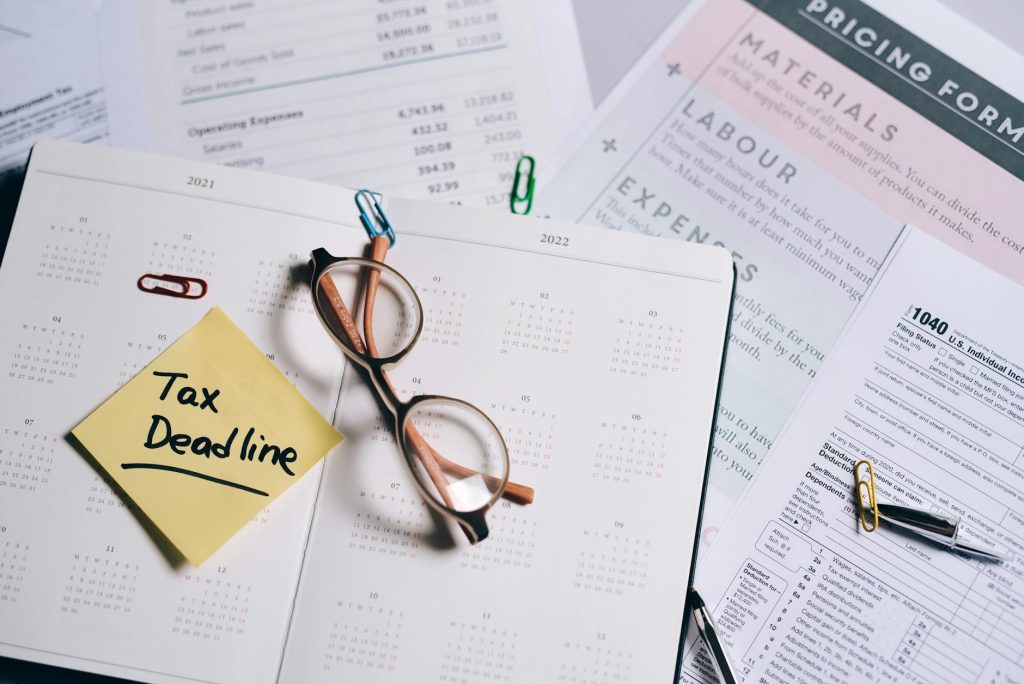 A calendar marked with "Tax Deadline" surrounded by financial documents and eyeglasses.