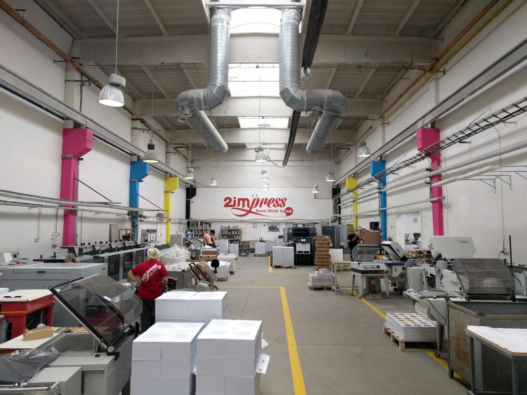 Spacious printing facility with modern machinery and workers engaging in tasks.