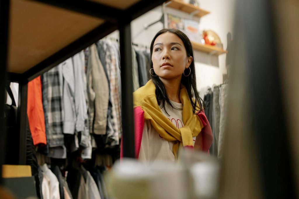 Young woman exploring trendy fashion at a thrift store, embracing vintage style.