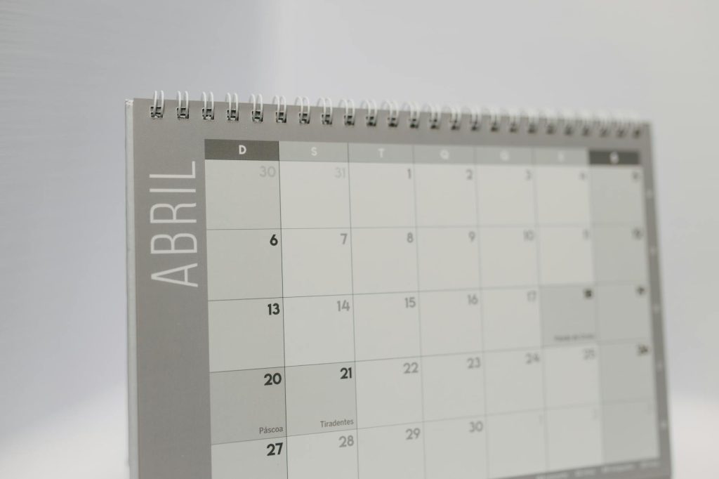 Close-up of a spiral-bound April desk calendar with a gray minimalistic design.
