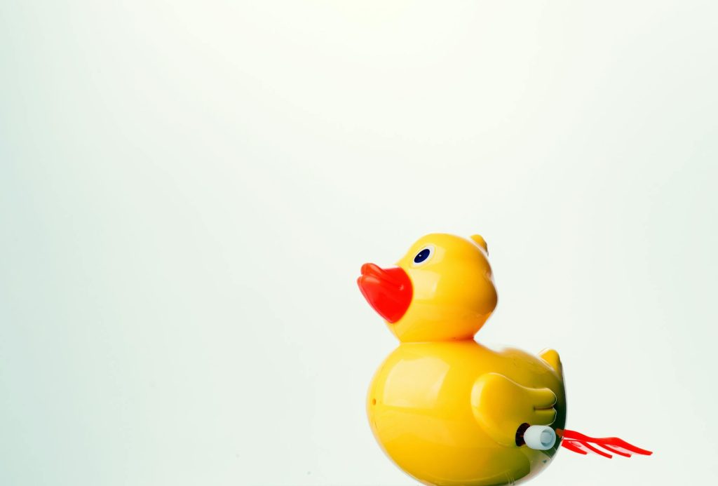 A bright yellow rubber duck toy against a plain white background with ample copy space.