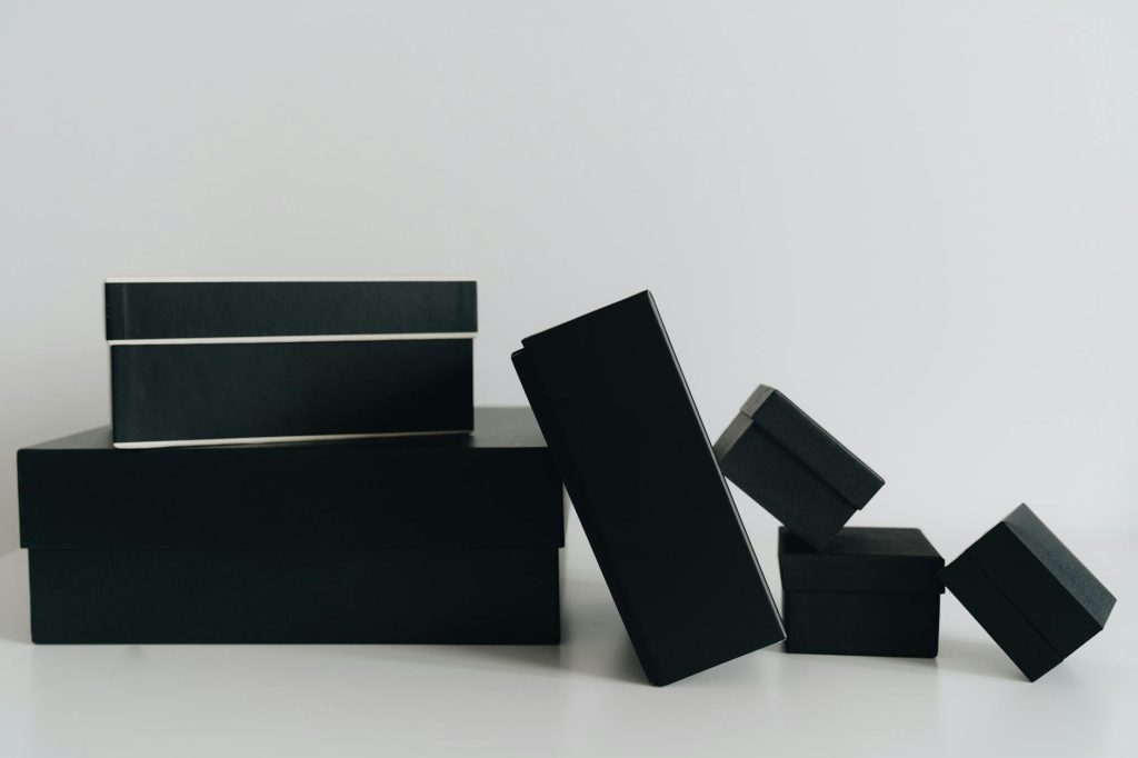 A minimalist display of black gift boxes of varying sizes against a white background.