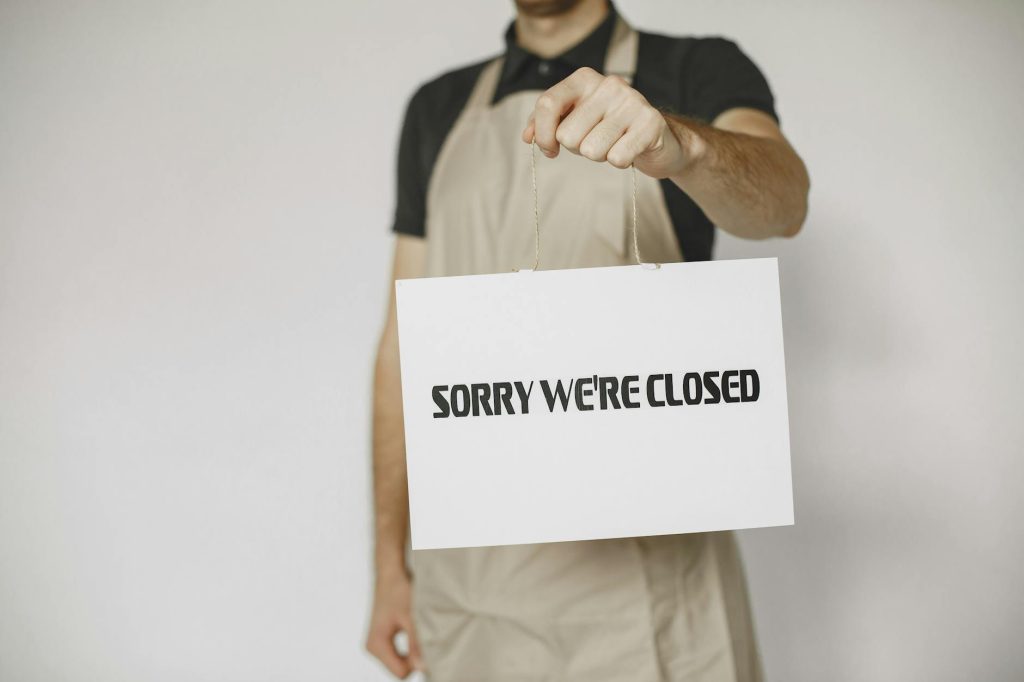 Close-up of a man holding a 'Sorry We're Closed' sign, ideal for business or retail concepts.
