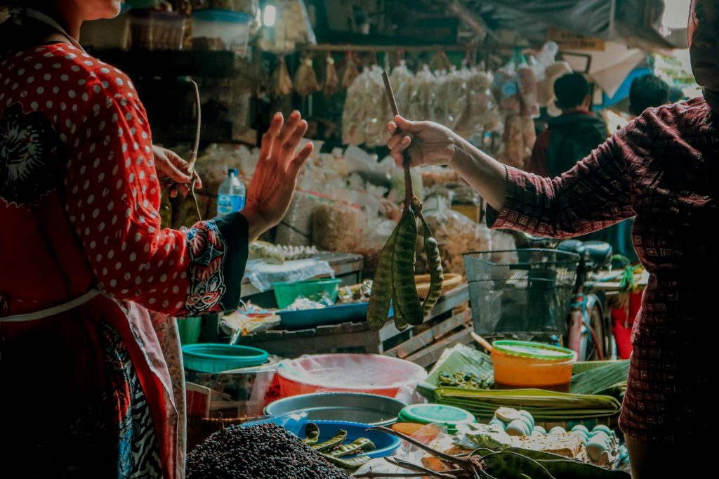 A vibrant street market in Indonesia with two women selling vegetables.