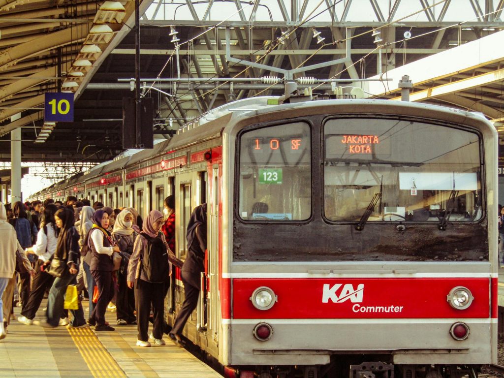 Crowded train platform with people boarding a KAI commuter in Jakarta, Indonesia.