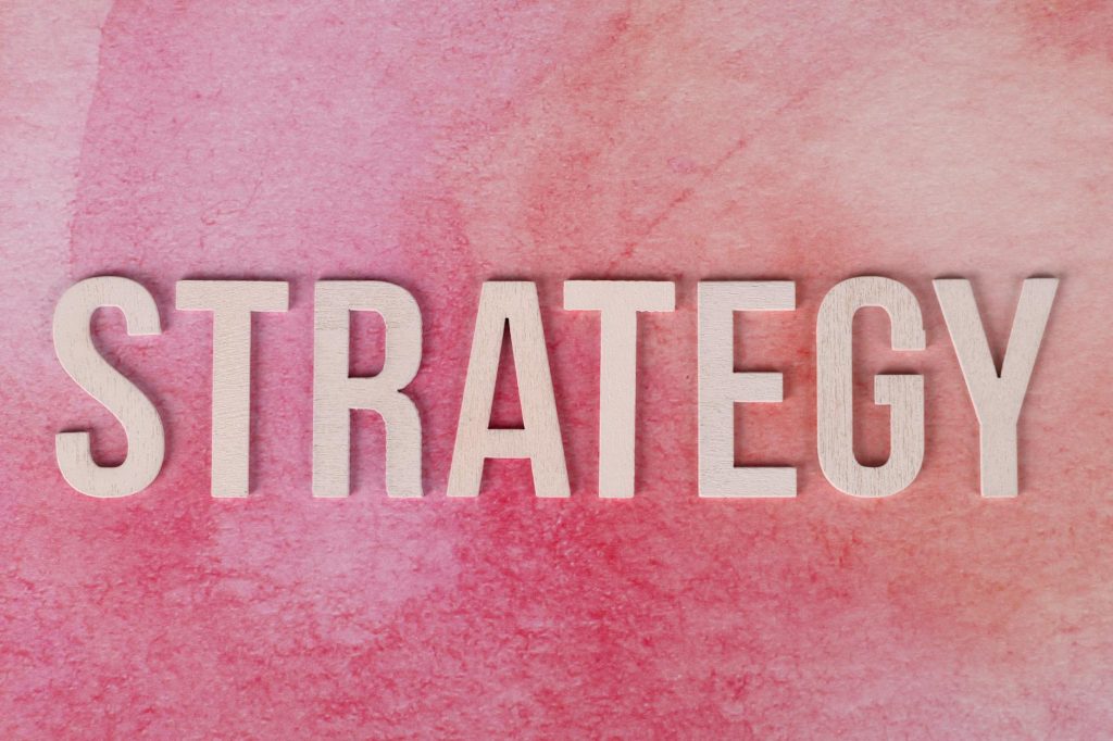 Wooden letters spelling 'Strategy' on a pink textured background.