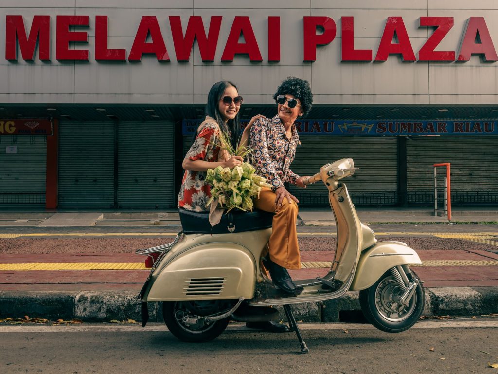 Stylish couple with flowers on a vintage scooter at Melawai Plaza, Jakarta.