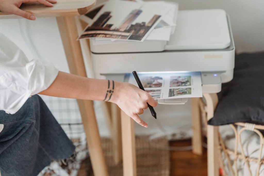 High angle of crop anonymous female photographer using printer for making images while working in flat