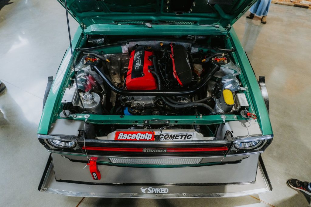 Overhead view of a modified vintage Toyota car engine at a car show.