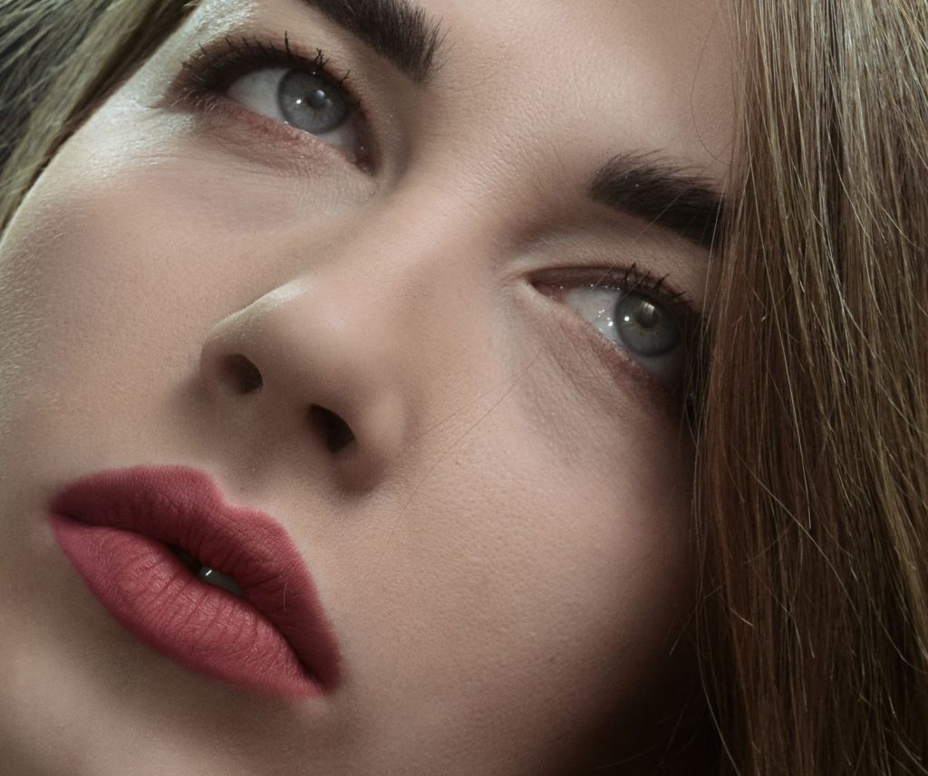 Artistic close-up portrait highlighting a woman's facial expression and bold makeup.