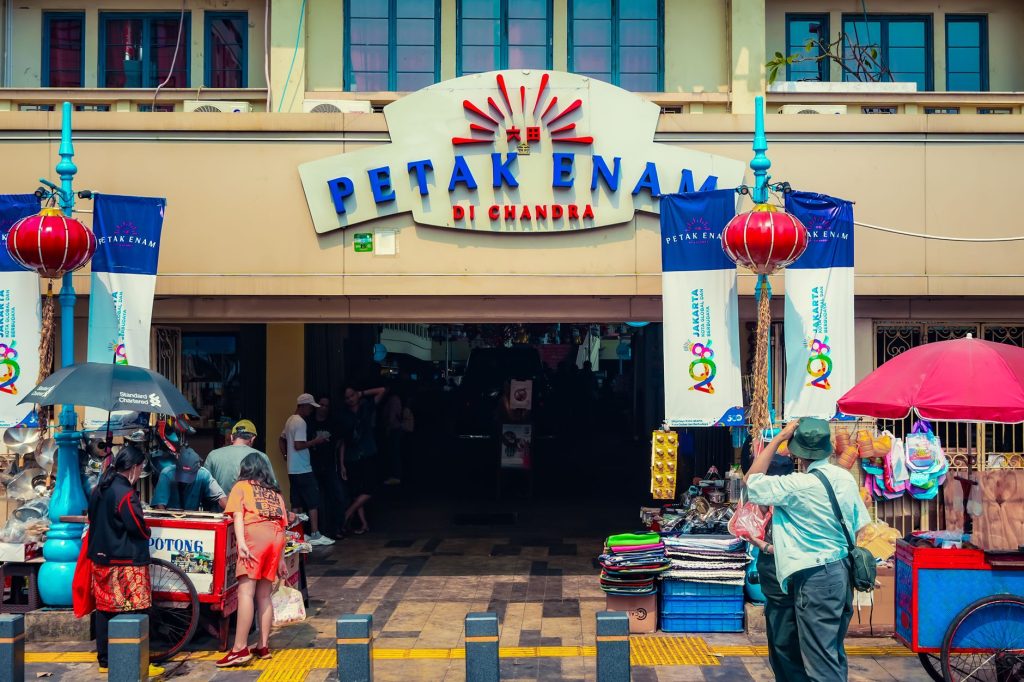 Colorful and lively scene at Petak Enam market entrance in Jakarta, Indonesia, capturing daily hustle and vibrant street life.