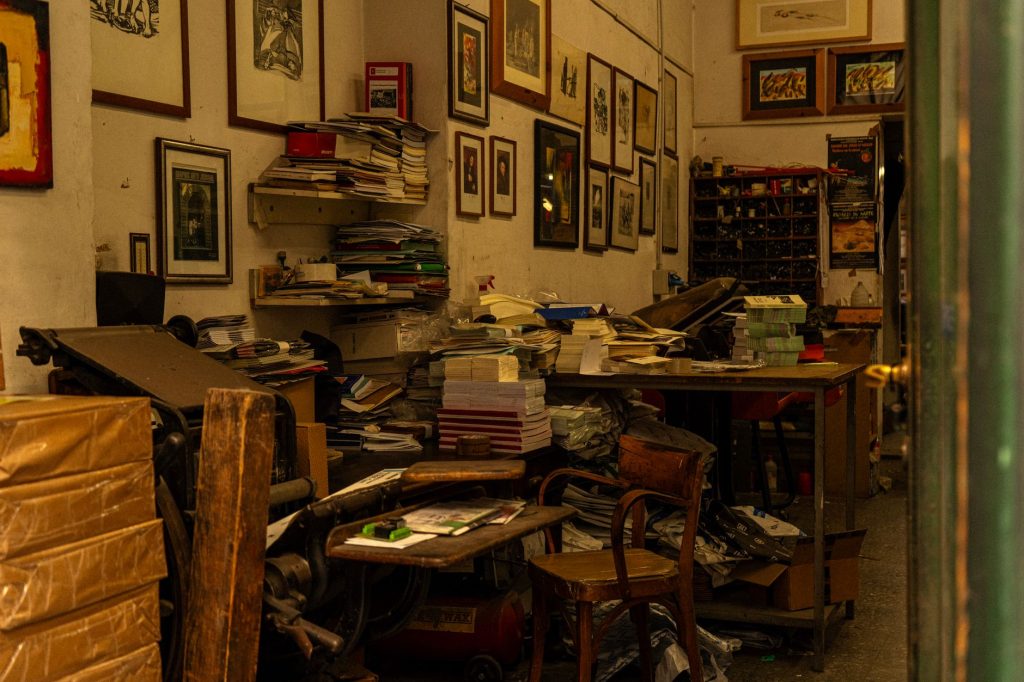 A cluttered vintage print shop interior in Florence, Italy, filled with books and artwork.
